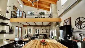 Une cuisine spacieuse dotée d’un grand îlot central, d’un coin repas et d’une mezzanine accessible par un escalier.