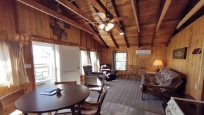 A wooden cabin interior with a dining table, chairs, a sofa, and a ceiling fan. - Roomy Cabin With Beautiful Views - Cabin 2.5 at Green Valley Resort (Nevis)
