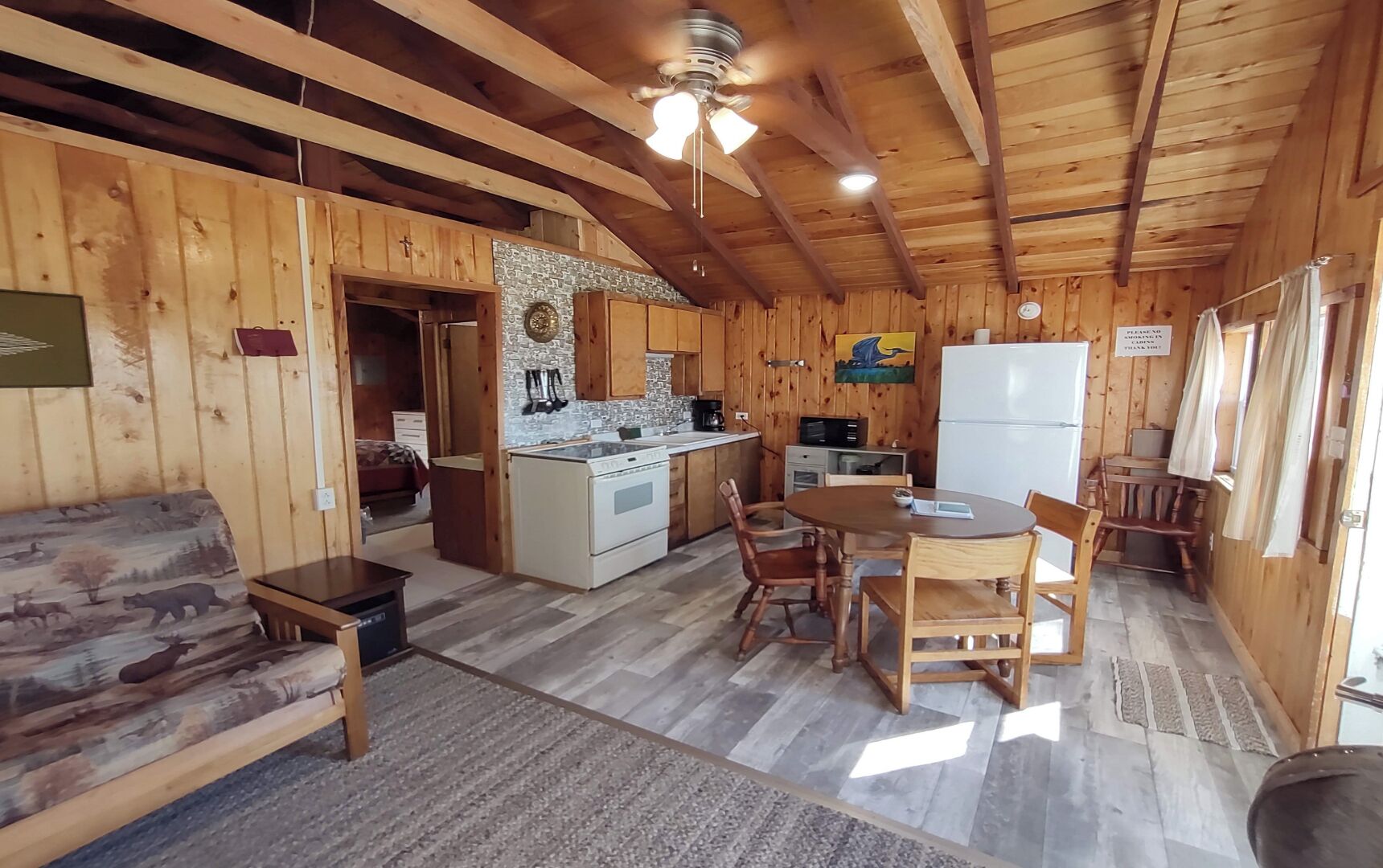 Ein Holzblockhaus-Interieur mit Küche, Essbereich und einer Couch.