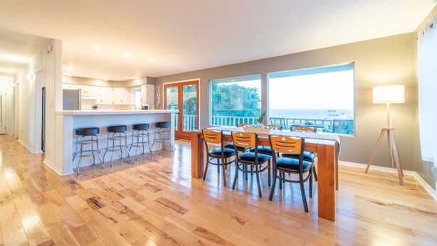Een ruime keuken met een centraal eiland, barstoelen en een eethoek met stoelen.