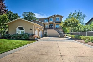 A two-story house with a driveway, a covered front porch, and a staircase leading to the second floor. - Luxe Getaway w/ Riverfront Views in Grants Pass! (Grants Pass)