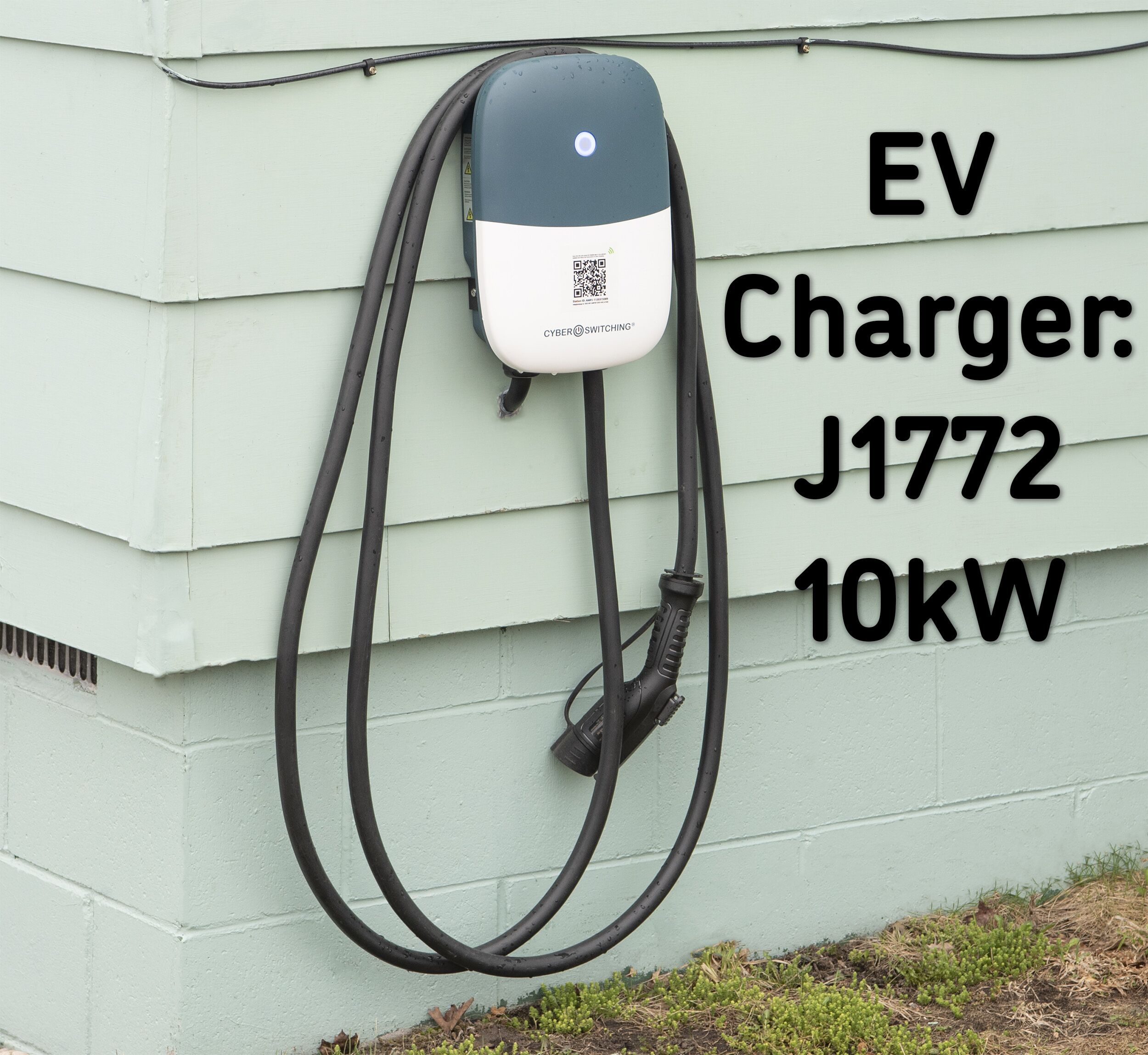 Eine EV-Ladestation mit dem Hinweis J1772 und einer Leistung von 10 kW, an einem hellgrünen Gebäude befestigt.
