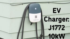 Un carregador per a vehicles elèctrics amb l'etiqueta J1772 i una capacitat de 10kW, fixat a un edifici de color verd clar.