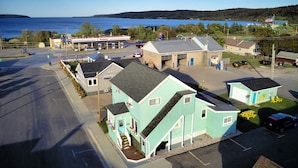 A small, light blue building with a porch and a staircase, located near a gas station and a parking lot. - SB2-Downtown Munising, Deli and Brewery Across the Street (Munising)