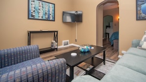 A living room with a sofa, a coffee table, a TV, and a painting on the wall. - SB2-Downtown Munising, Deli and Brewery Across the Street (Munising)