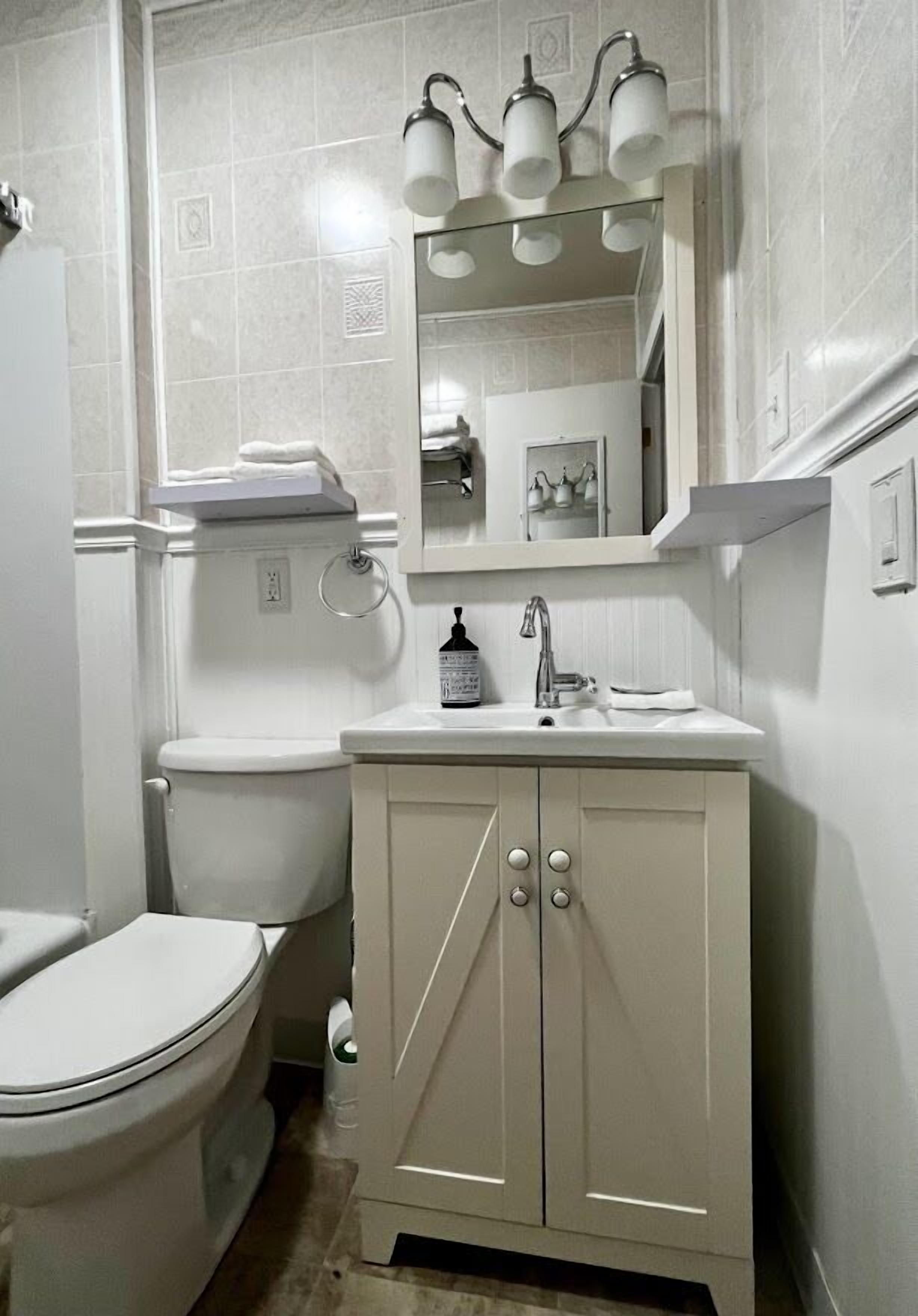 A bathroom with a toilet, sink, and mirror.