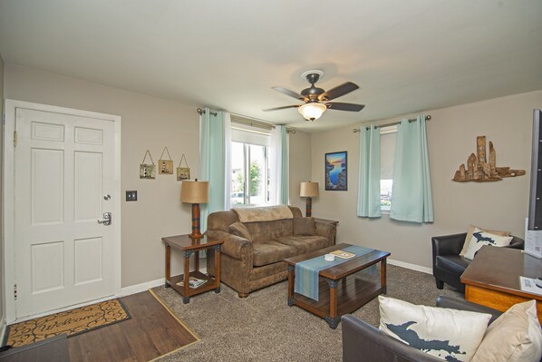 A living room with a ceiling fan, a sofa, a coffee table, and a side table with lamps.