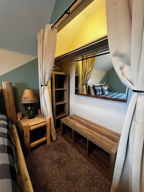 A cozy room with a wooden bench, a small table with a lamp, and a mirror on the wall.