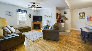 Un salon avec une cheminée, un téléviseur et un ventilateur de plafond.