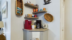 Une cuisine décorée sur le thème du café, avec notamment un panneau indiquant un bar à café, une horloge sur le thème du café et diverses tasses à café disposées sur des étagères.