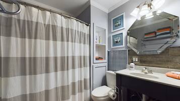 A bathroom with a striped shower curtain, a toilet, a sink with a mirror, and a towel rack.