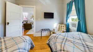 A room with two beds, a TV, a chair, and a window with curtains. - SSVR2-Spacious, Downtown Munising Apartment (Munising)