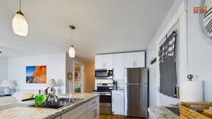 A modern kitchen with white cabinets, stainless steel appliances, and a marble countertop.