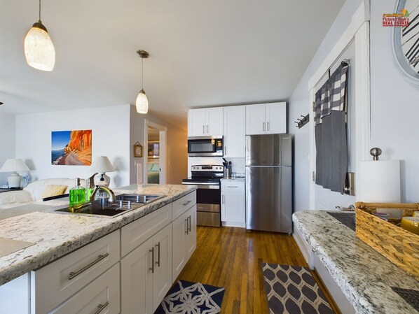 A modern kitchen with white cabinets, stainless steel appliances, and a marble countertop.