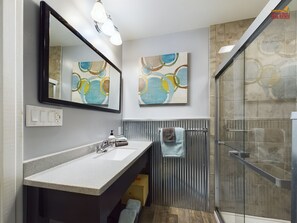 A modern bathroom with a large mirror, a sink, and a shower area.