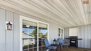 A covered porch with a grill, two chairs, and a lantern.
