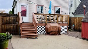 Una casa con terraza, una parrilla techada y una valla de madera.
