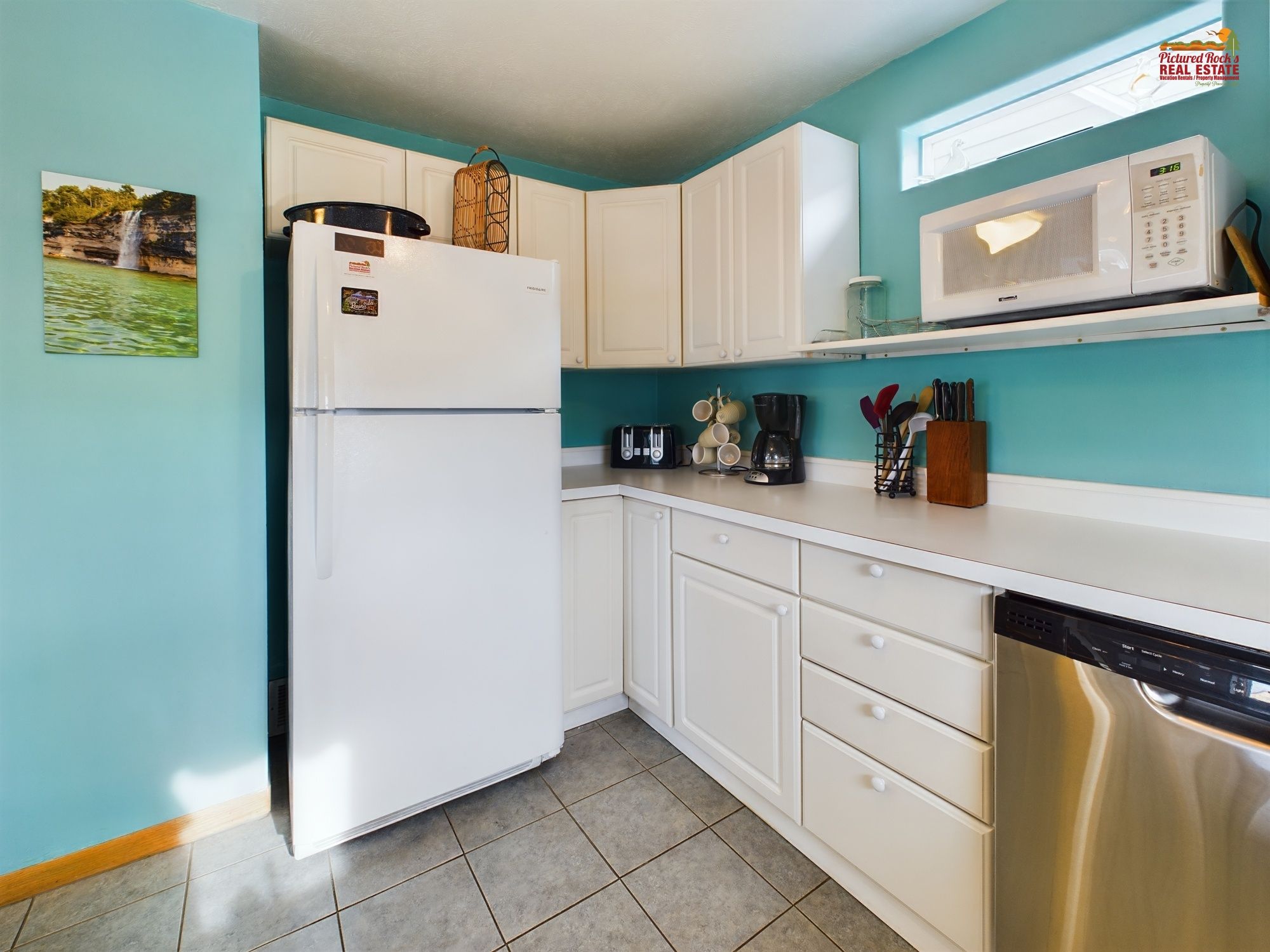 A kitchen with white cabinets, a stainless steel dishwasher, a microwave, and a coffee maker.
