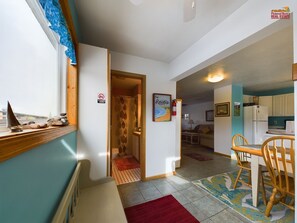 A compact living space with a kitchenette, a dining area, and a bathroom. - Rock House-Downtown Munising with Private Patio, Garage, Fire-pit & BBQ Grill (Munising)