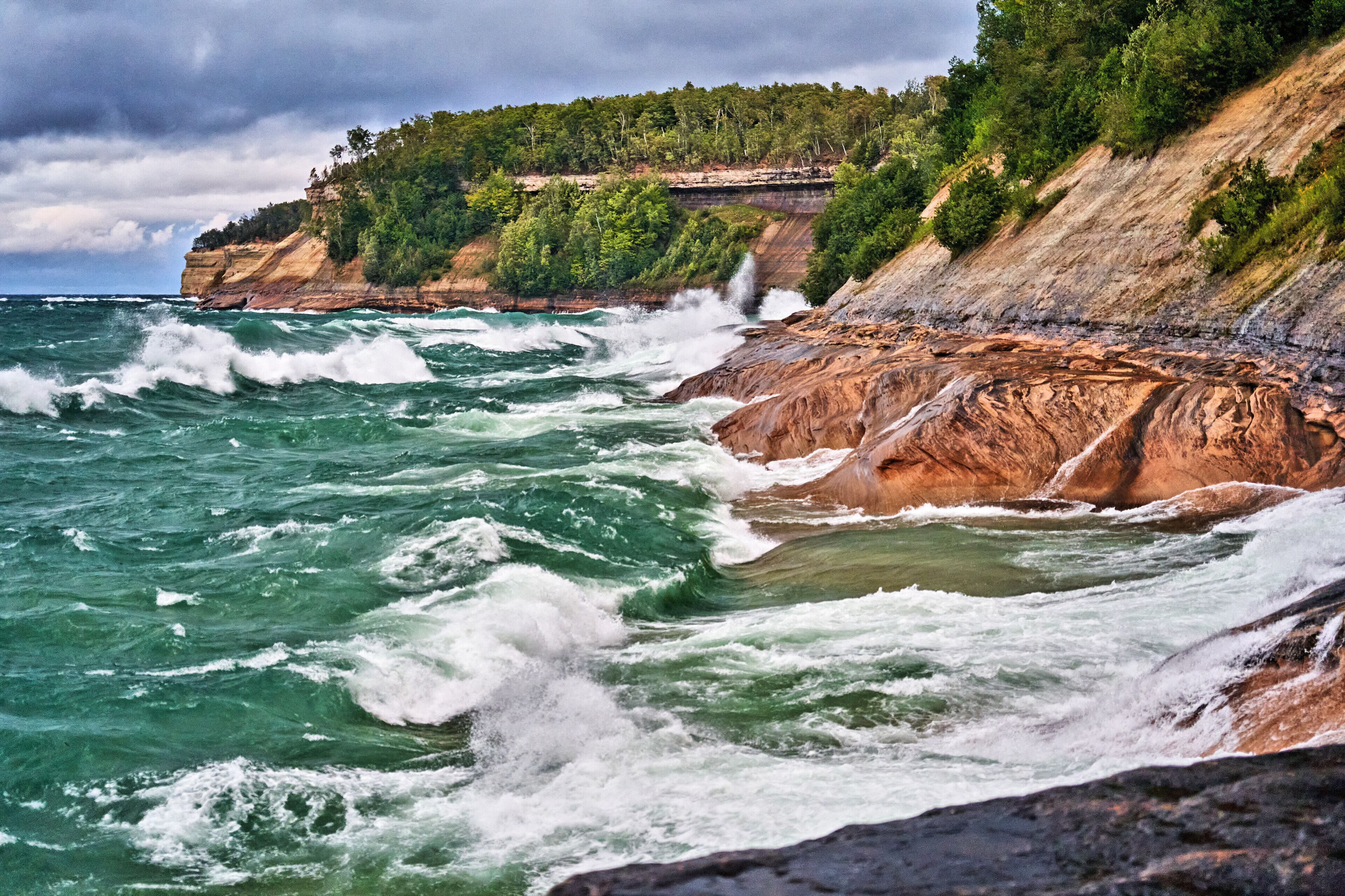 Un paisaje costero con acantilados rocosos y olas rompiendo contra la orilla.