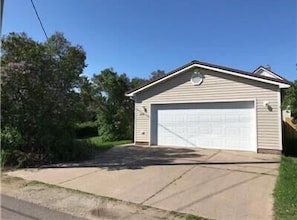 Een gelijkvloers huis met garage, omgeven door groen.