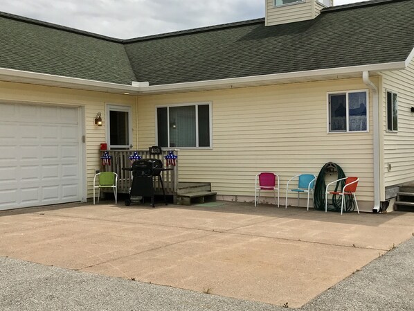 A house with a garage, a patio with a grill, and several chairs.