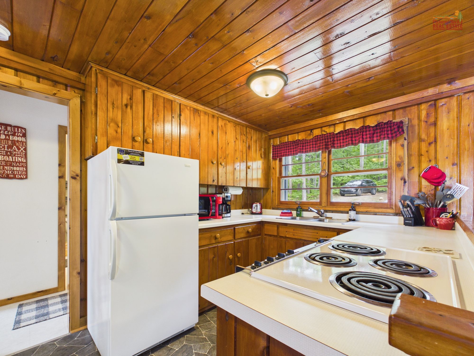 Cocina de cabaña de madera con refrigerador, estufa y microondas.