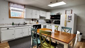 Une cuisine compacte avec des meubles blancs, une table à manger en bois et une fenêtre donnant sur un beau paysage.