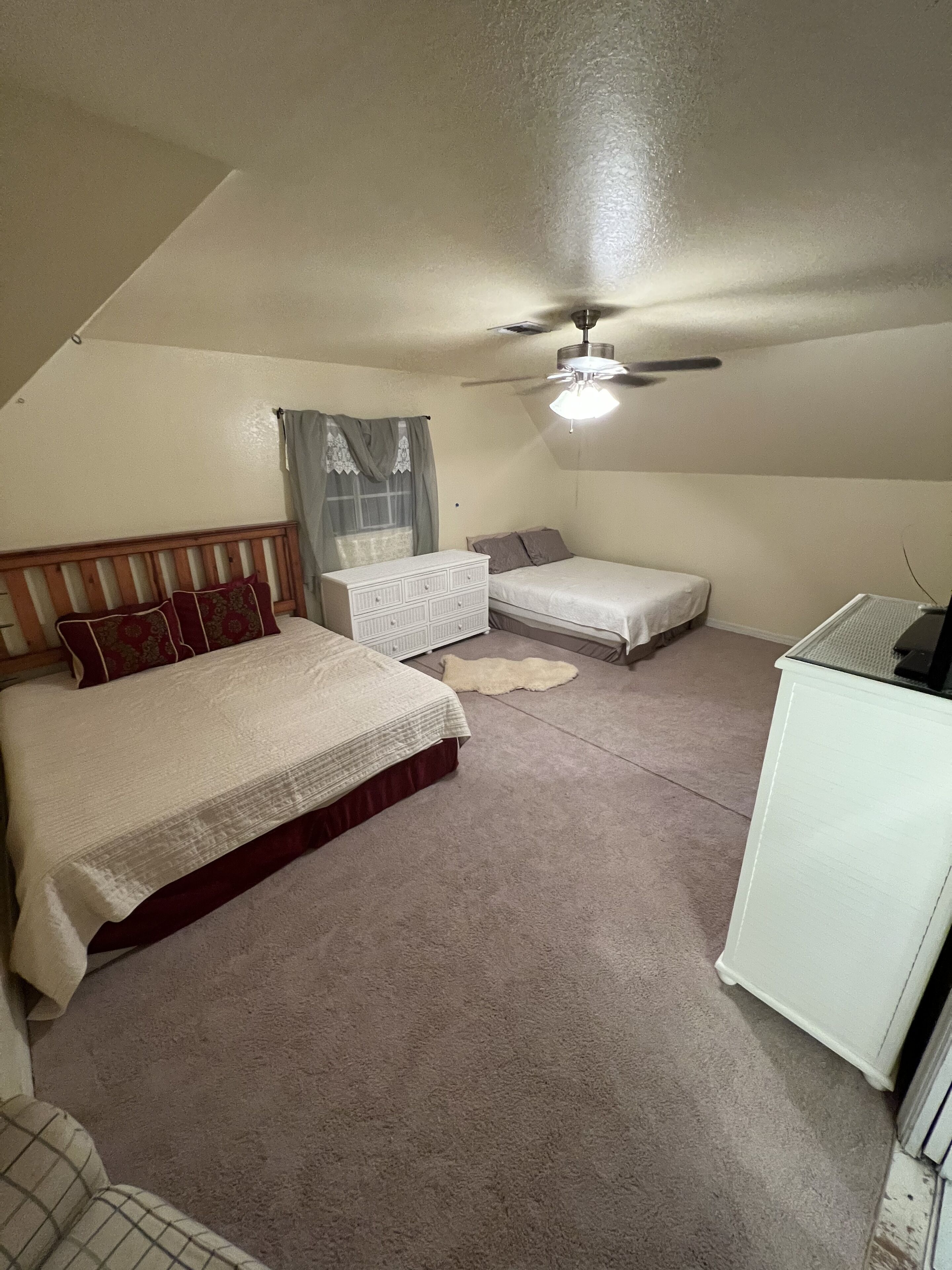 Quarto com cama, cômoda, escrivaninha e ventilador de teto.