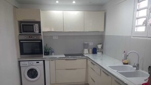 A compact kitchen with built-in appliances, a sink, and a window.