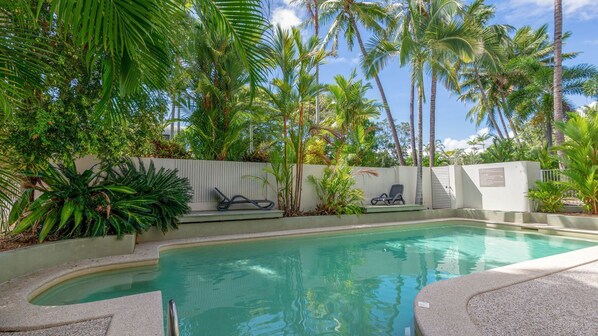 A pool area with lounge chairs and palm trees. - Tropical Escape Port Douglas (Port Douglas)