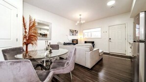 A modern living room with a dining area, a sofa, and a kitchen area with a refrigerator. - Chic Suite - Long Stays - King Bed  - Fireplace &WiFi
 (Edmonton)