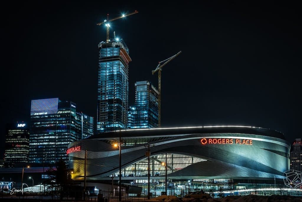 A modern stadium with a curved roof and the name "Rogers Place" on the facade.