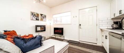 A modern living room with a sofa, a flat-screen TV, and artwork on the wall.