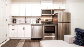 A compact kitchen with white cabinets, a microwave, a refrigerator, and an oven. - Chic Suite - Long Stays - King Bed  - Fireplace &WiFi
 (Edmonton)