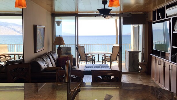 A modern kitchen with a large island, a dining area with a view, and a seating area with a sofa and chairs.