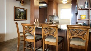 A kitchen with wooden bar stools, a painting, and a modern faucet.