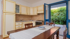 A kitchen with white cabinets, a stove, and a dining table with chairs. - All have their own entrance and are located in four-family villas.Elegantly furnished, they have a small garden with furnished covered veranda or furnished covered terrace.Composed of living room with kitchenette and sofa, bedroom with double bed, room w (Monte Petrosu)