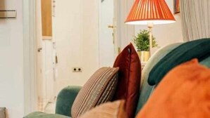 A room with a green sofa, a red lamp, and a door leading to another room.