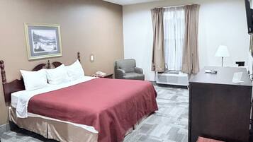 A hotel room with a bed, a desk, a chair, a television, and a picture on the wall.