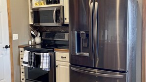 A modern kitchen with stainless steel appliances, including a refrigerator and microwave, and wooden flooring. - Store that boat inside!  Blocks to boat ramps/Marina & Restaurant (Chamberlain)