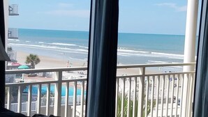 A balcony with a view of the beach and ocean.