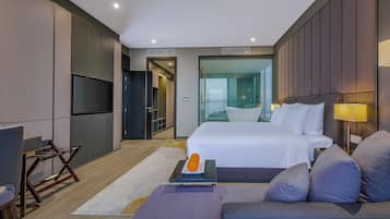 A modern hotel room with a large bed, a sofa, a desk, and a TV.