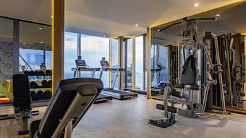 A modern gym with treadmills, weight machines, and a view of the sea.