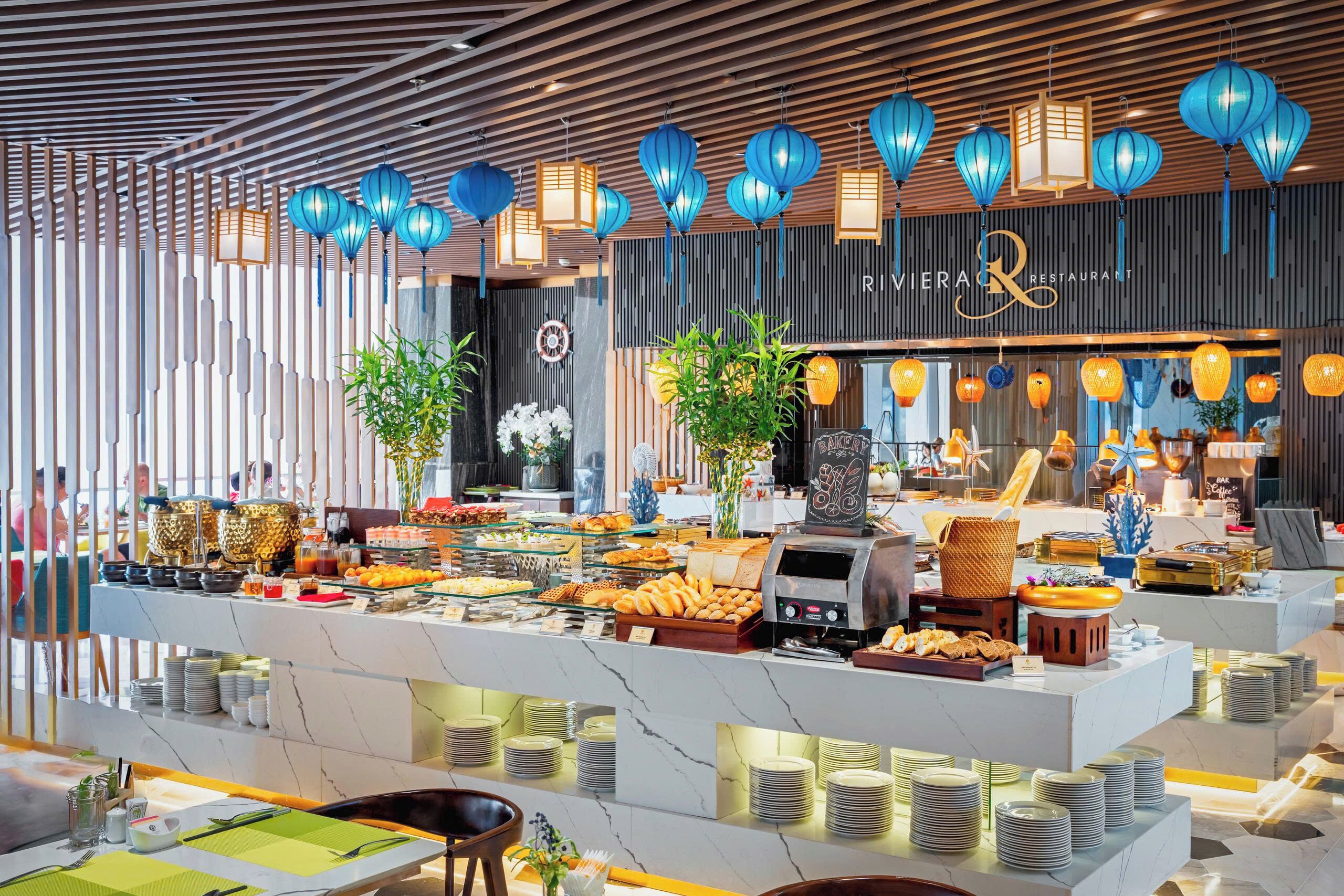A buffet setup with various food items, a coffee machine, and a seating area with tables and chairs.