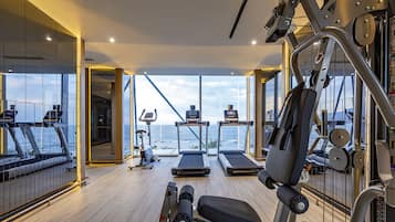 A gym with treadmills, a bench press, and a rowing machine, overlooking a body of water.