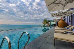 An infinity pool with lounge chairs and umbrellas, overlooking a body of water. - Le Sands Oceanfront Danang Hotel (Da Nang)