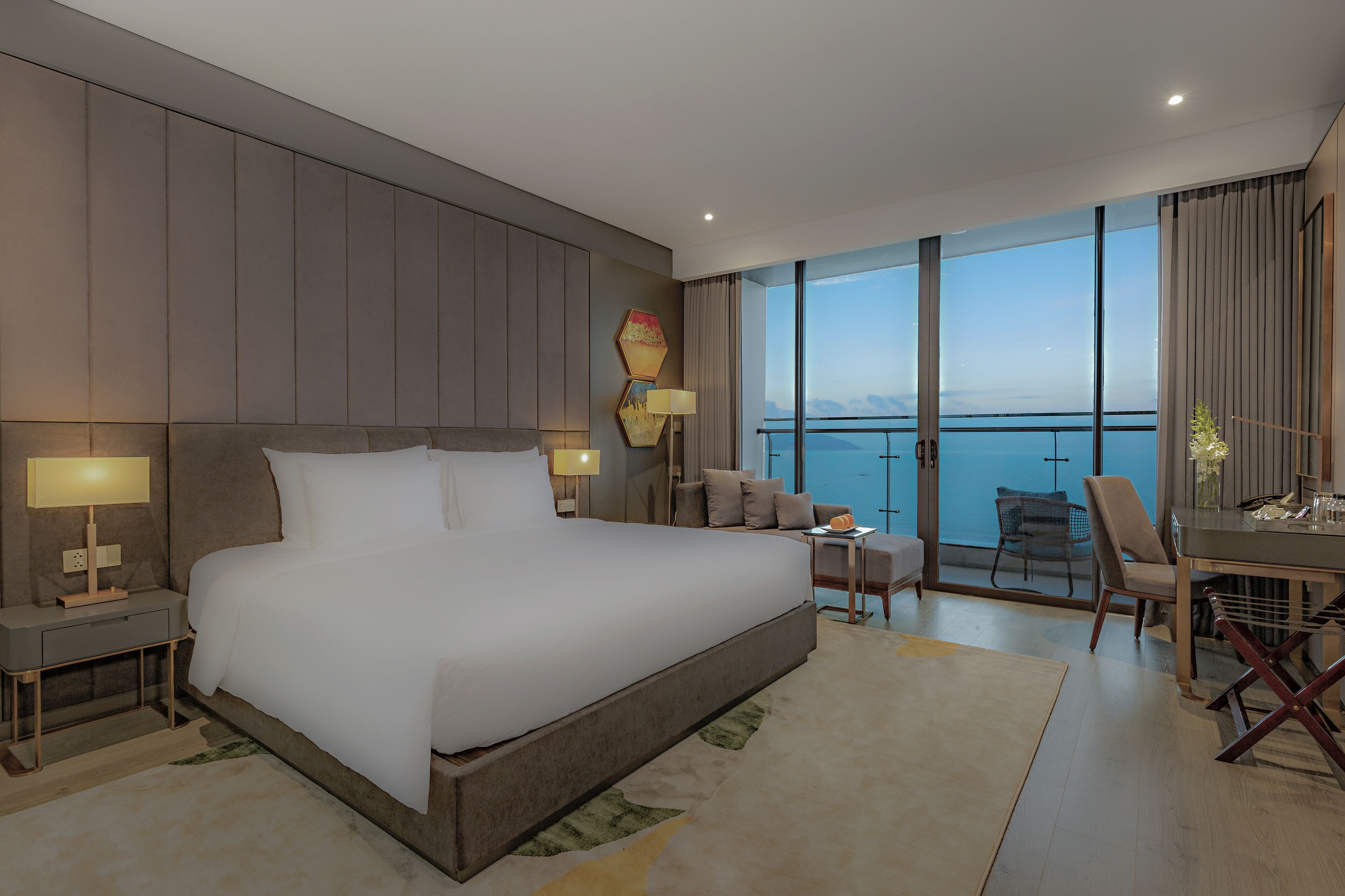 A modern hotel room with a large bed, a balcony with a view, and a dining area.