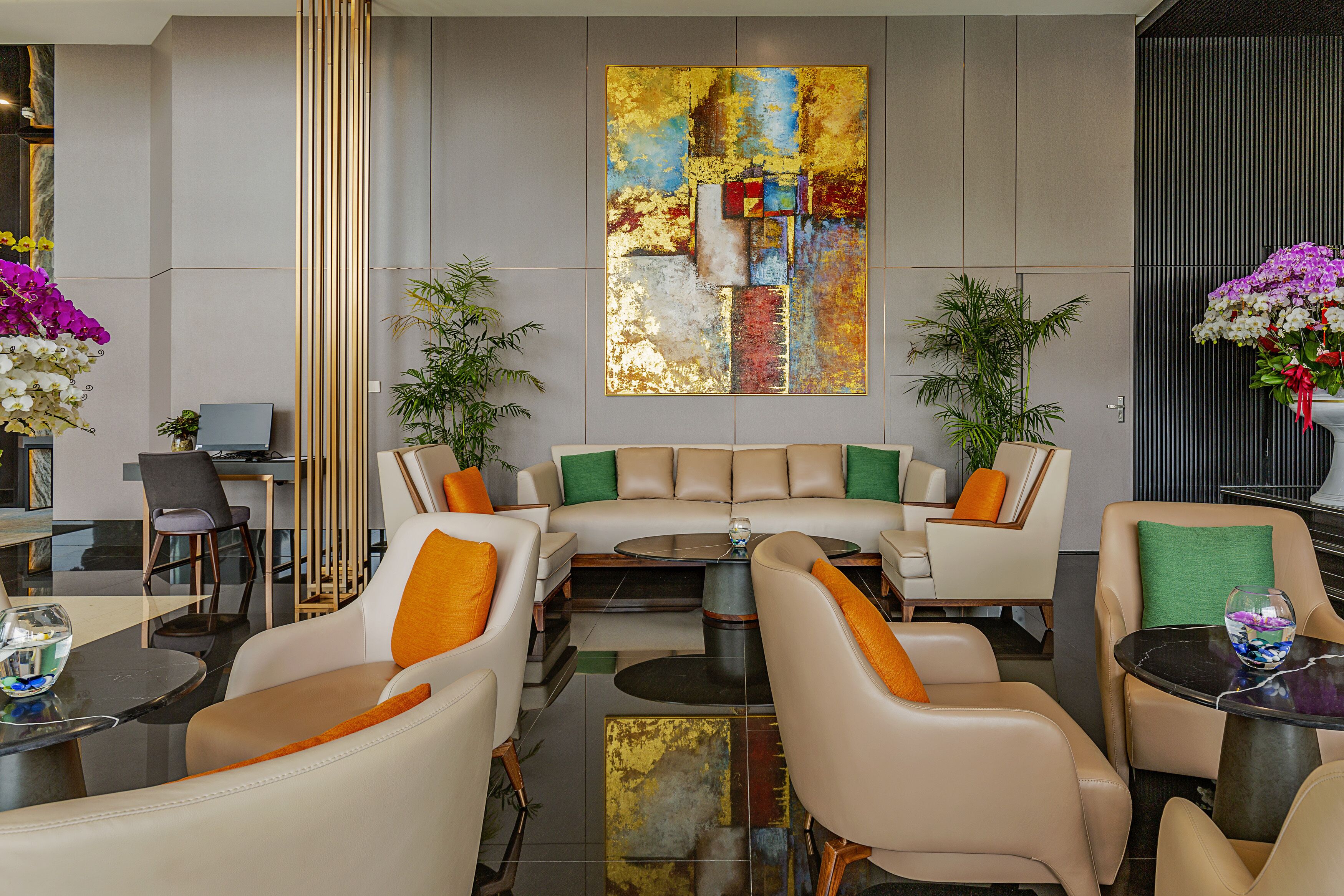 A modern hotel lobby with a sofa set, armchairs, a coffee table, and a large abstract painting on the wall.