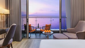 Una habitación de hotel moderna con balcón, escritorio, dos sillas y cama.